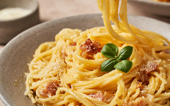 Pasta carbonara con trozos de panceta y albahaca