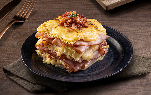 Lasaña de jamón y queso en plato oscuro