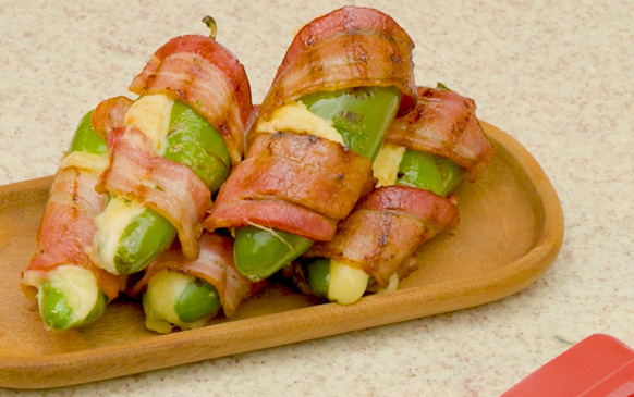Chiles jalapeños rellenos de queso y envueltos en tiras de tocino dorado.