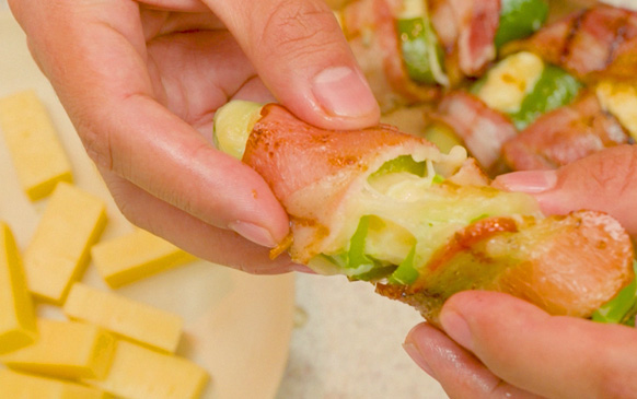 Chiles jalapeños rellenos de queso y envueltos en tiras de tocino dorado.