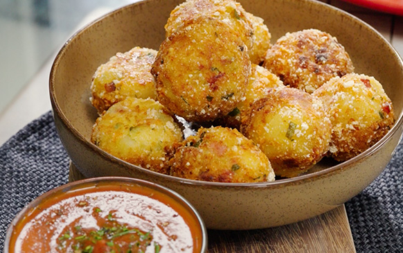 Croquetas doradas de jamón ahumado con salsa roja al lado